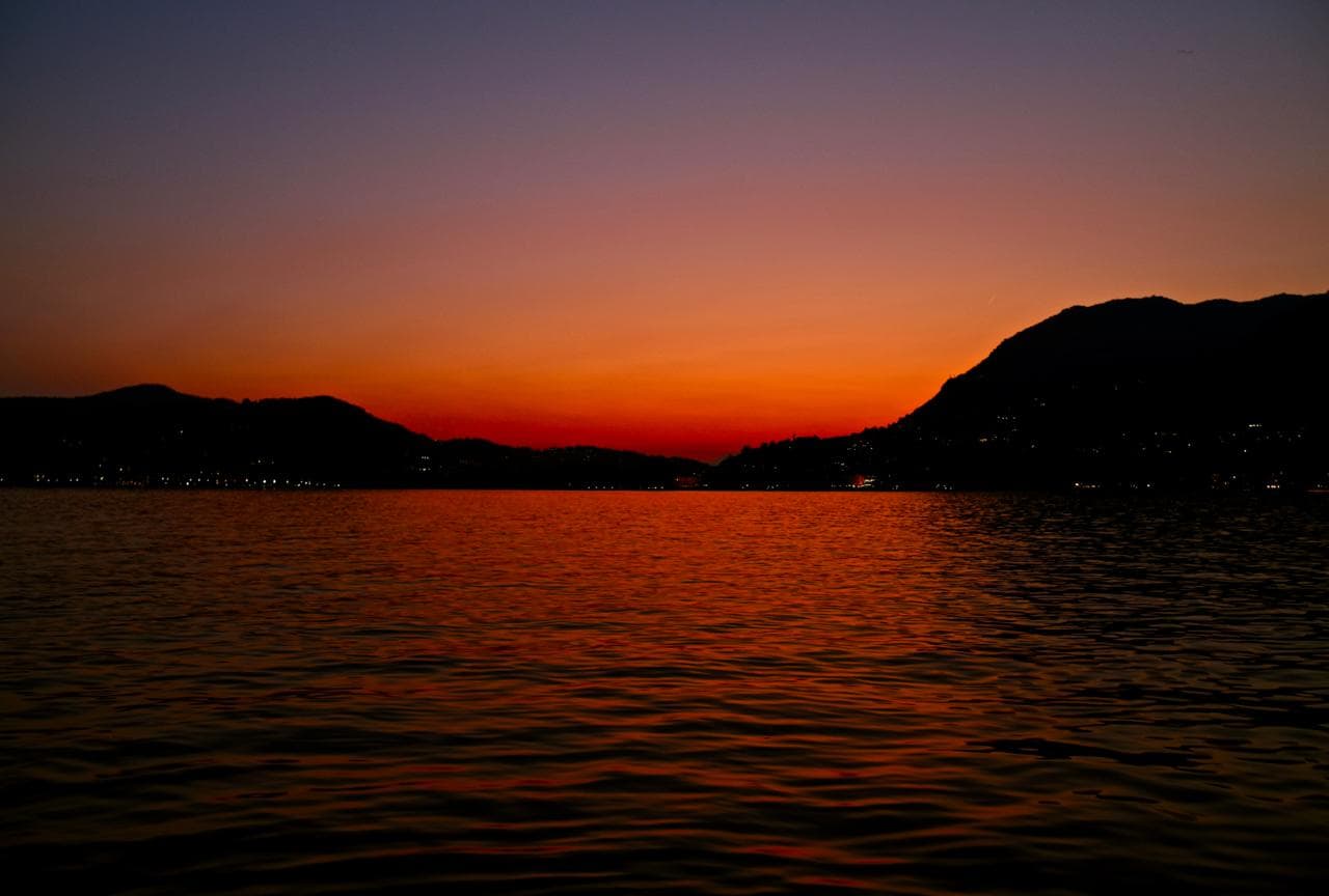 Couple relaxing on a private Cranchi boat with prosecco as the sun sets over Lake Como's mountains