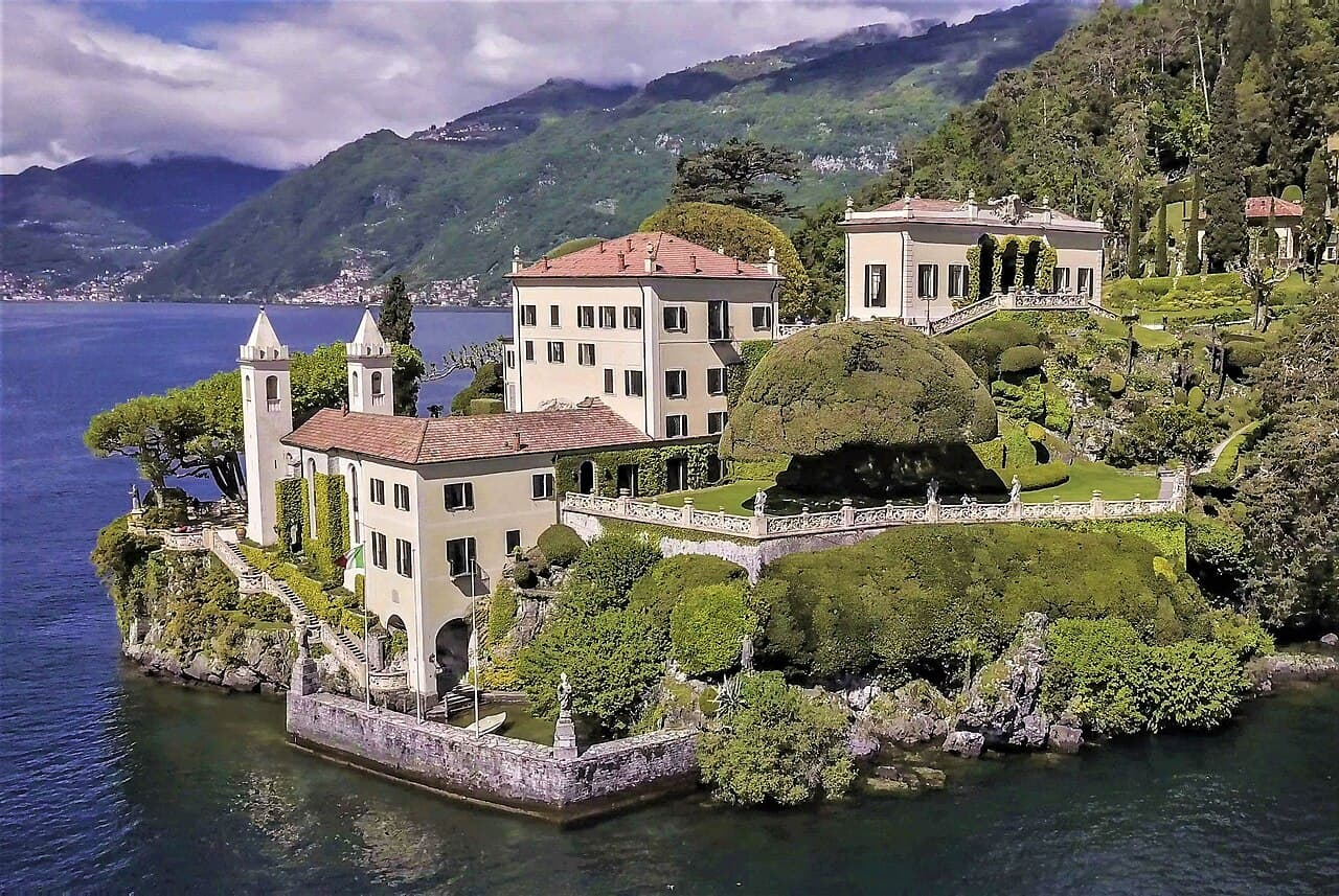 Villa del Balbianello's terraced gardens and Loggia Durini rising above Lake Como, seen from a private boat on the water